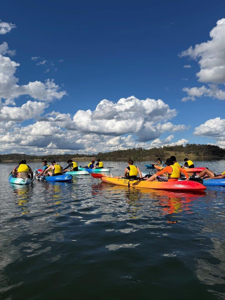 A student swimming their overturned kayak to shore